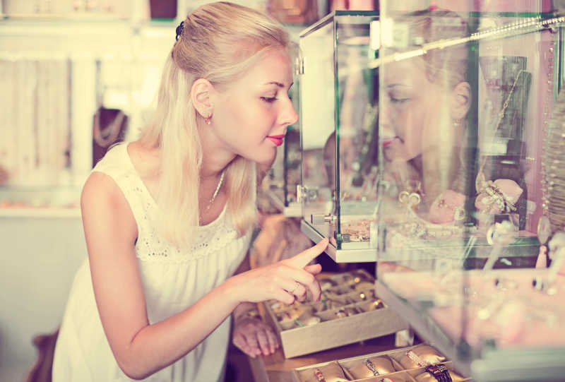 在玻璃展柜前看珠宝首饰年轻女人