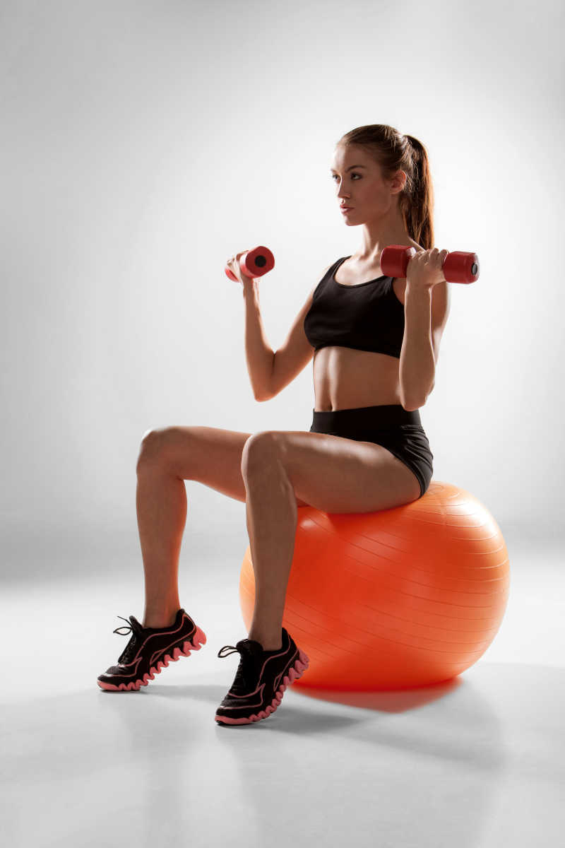运动的女人做有氧运动与红色哑铃健身