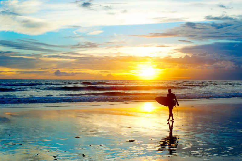 巴厘岛日落海滩上的冲浪者