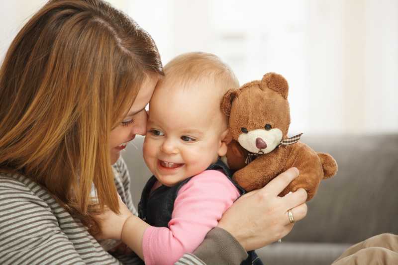 拥抱着泰迪熊和小婴儿的快乐妈妈