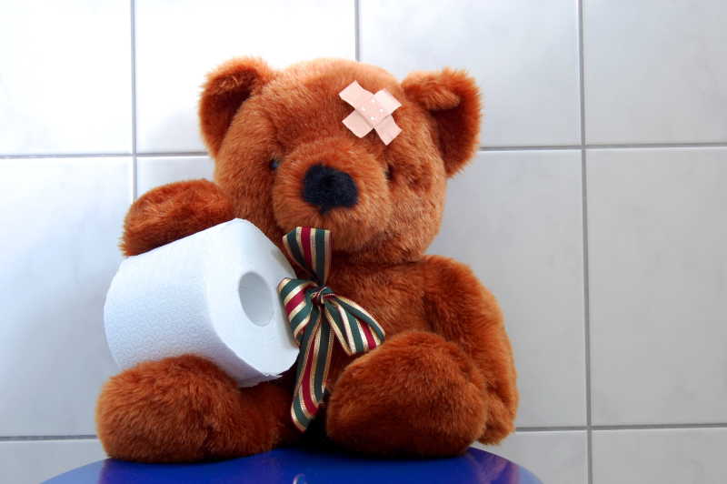 玩具泰迪熊带着纸巾坐在厕所里