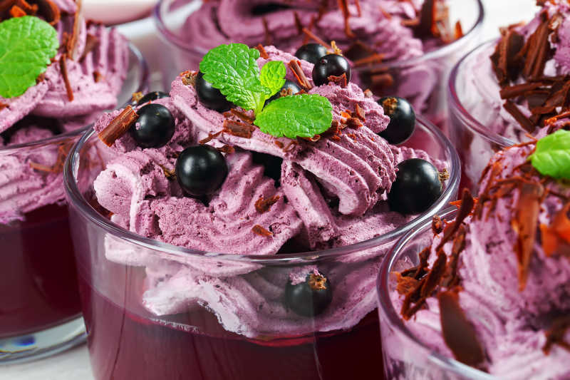 分层果冻和冰淇淋甜点芝士黑加仑浆果的奶油和酸奶用薄荷叶特写