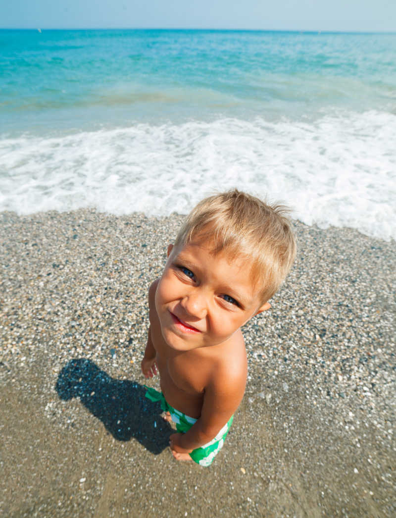 海滩上小男孩抬头看着镜头