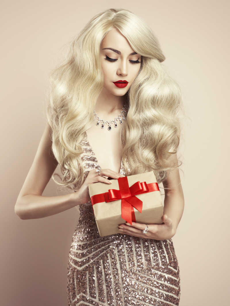 金色背景下的金发美女与圣诞礼物