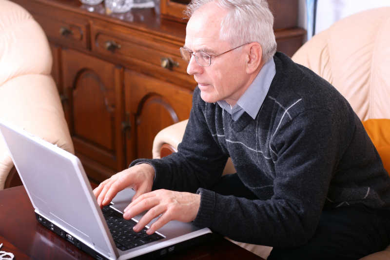 老人使用笔记本电脑工作