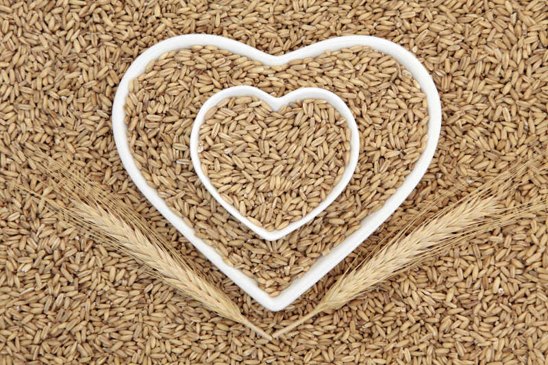 燕麦米的健康食品的谷物和小麦叶鞘形成心形碗的背景
