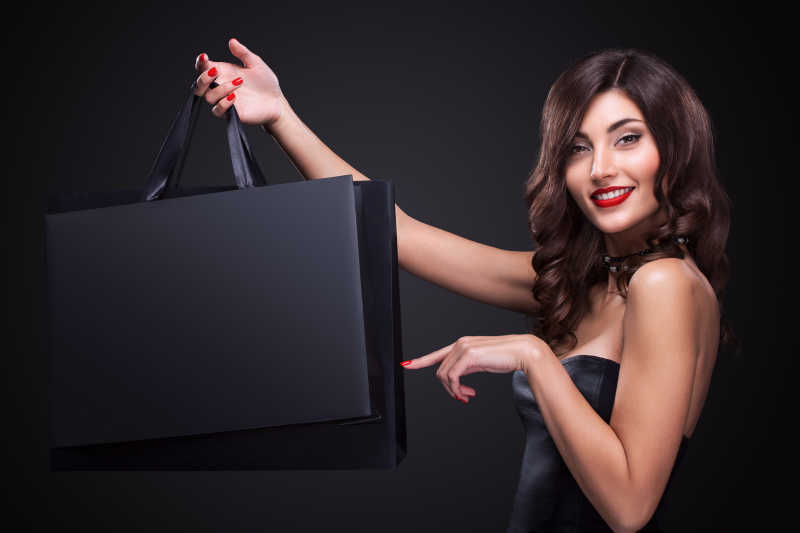 美丽的微笑女人展示购物袋使她竖起黑色星期五假期