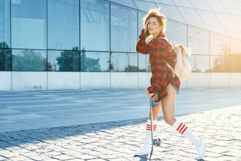 玩滑板的时髦红色格子衫女孩