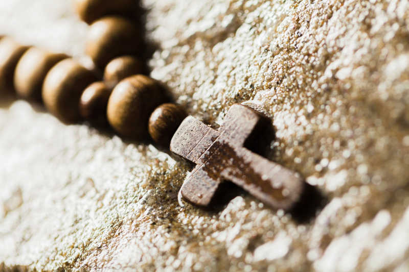 沙石上放置的木制十字架珠链