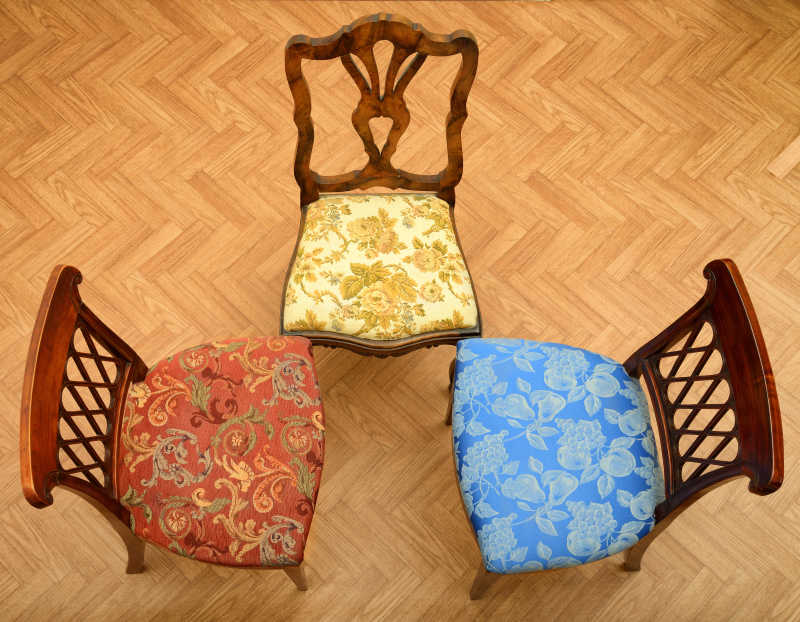 放在木地板上的三张老式的带有坐垫的靠背椅
