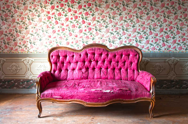 鲜花背景墙前边的粉色破损的沙发