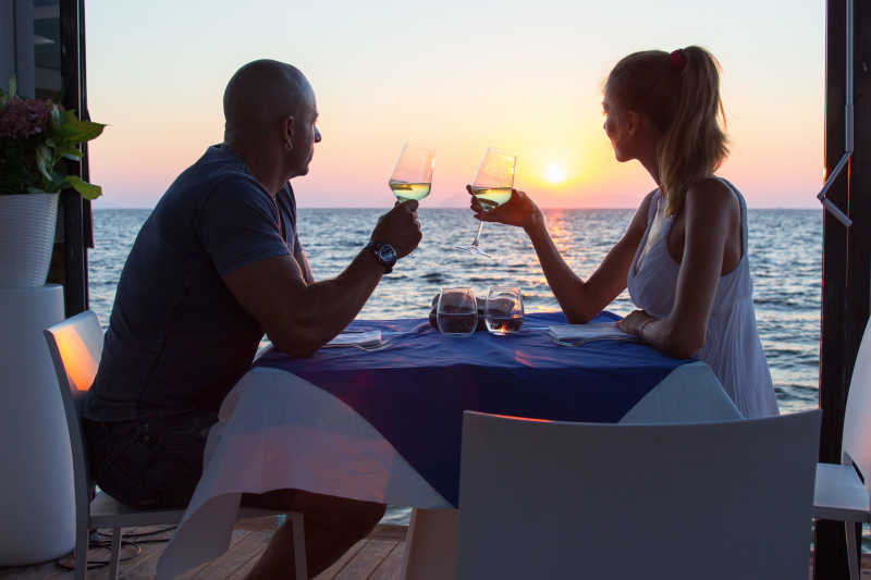 在海边餐厅拿着酒杯共同眺望远方的情侣