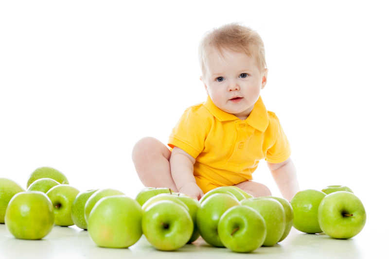 坐在绿色的苹果中微笑的男婴