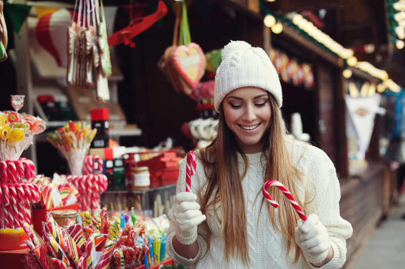 微笑的年轻漂亮的女人在选择糖果