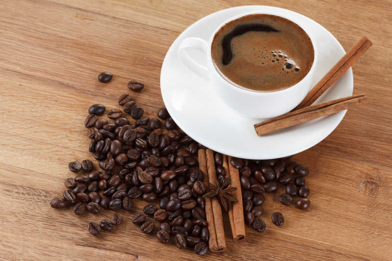 咖啡杯和豆肉桂枝大茴香放在木桌上棕色背景
