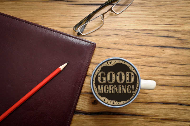 木桌上的早餐咖啡和工作笔记本笔