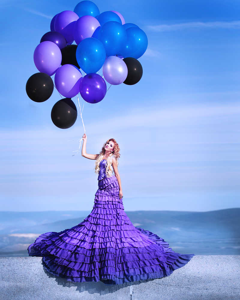 穿紫色连衣裙的漂亮女孩拿着气球
