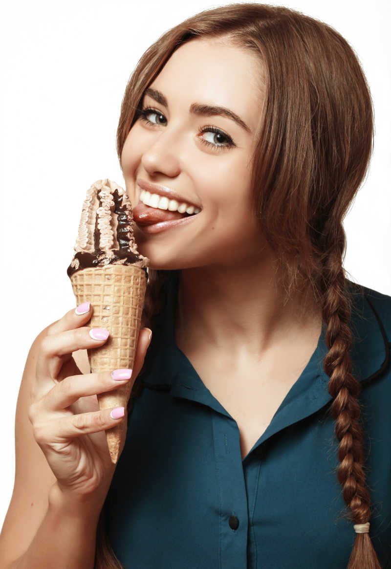 穿着绿松石裙子的可爱女孩正在吃巧克力冰淇淋