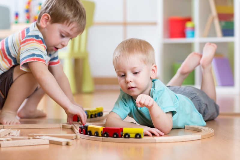 两个孩子在一起玩幼儿园的轨道火车玩具