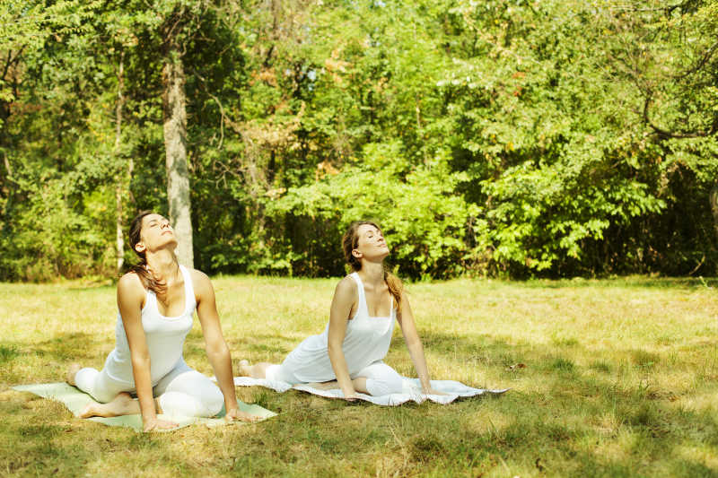 两个年轻女子在户外草地上做瑜伽