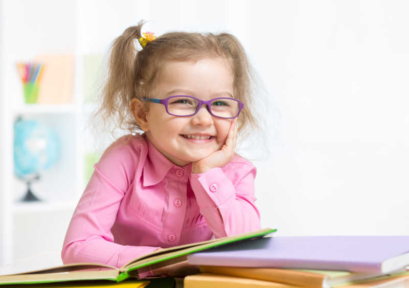 教室里戴着眼镜看书的微笑女孩