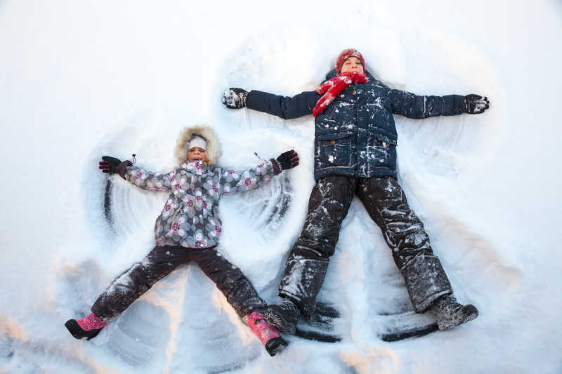 一起躺在雪地里的快乐中年女性和小女孩