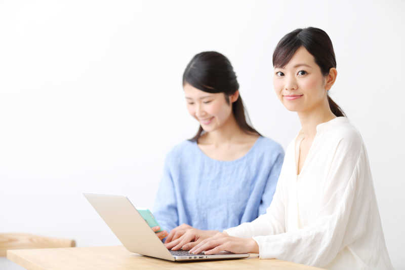 两位年轻女性在使用笔记本电脑工作