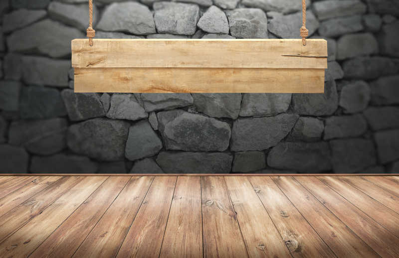 石墙背景中的挂木标志的木桌