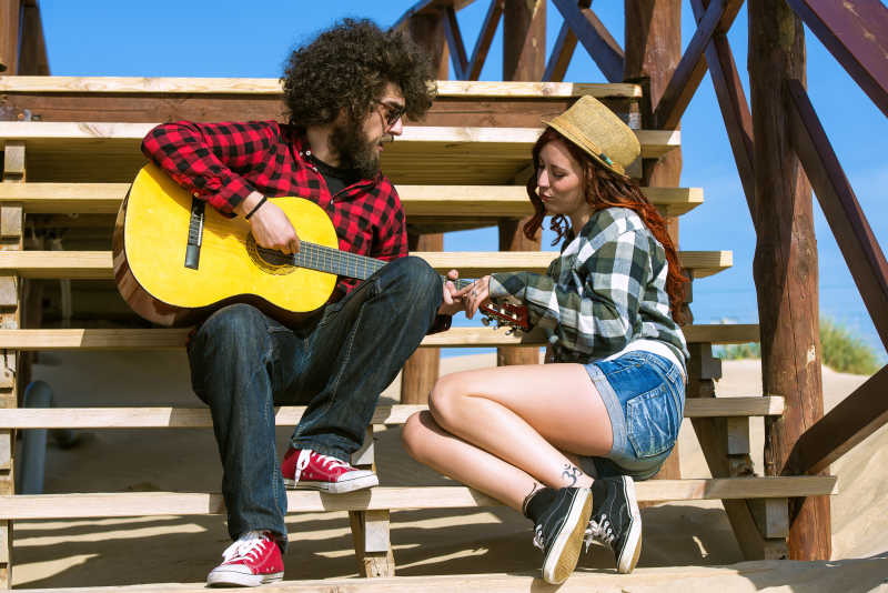 年轻男子在台阶上为女友弹吉他