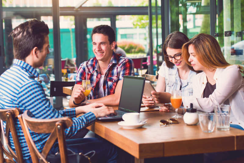一群坐在咖啡馆聊天使用电脑的年轻人
