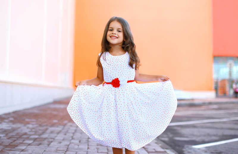 穿着白色的裙子在户外玩得很开心的小女孩