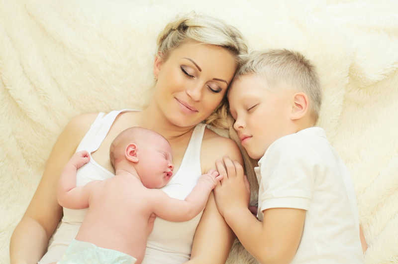 年轻的母亲和两个孩子躺在床上睡觉