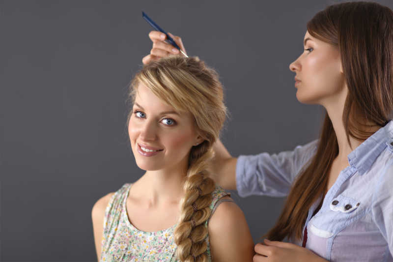年轻女子美发师在给女孩做发型