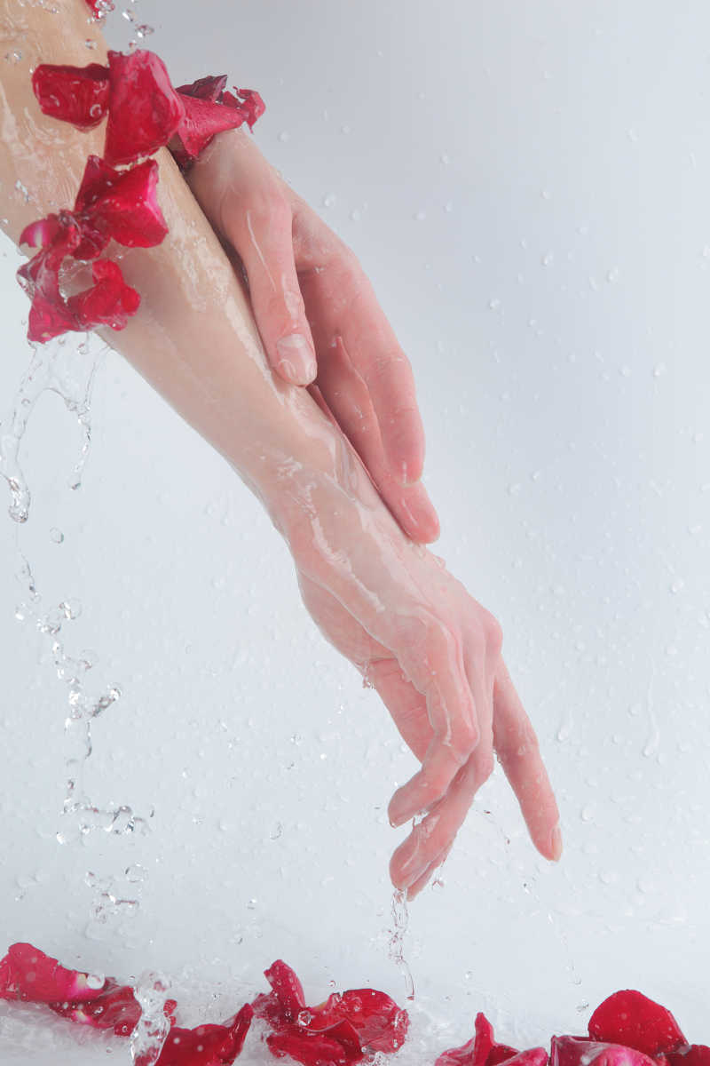 SPA会所用玫瑰和流动的水清洗女人的手