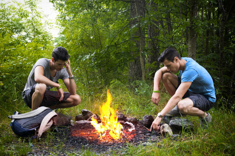 在篝火旁露营的两个年轻人