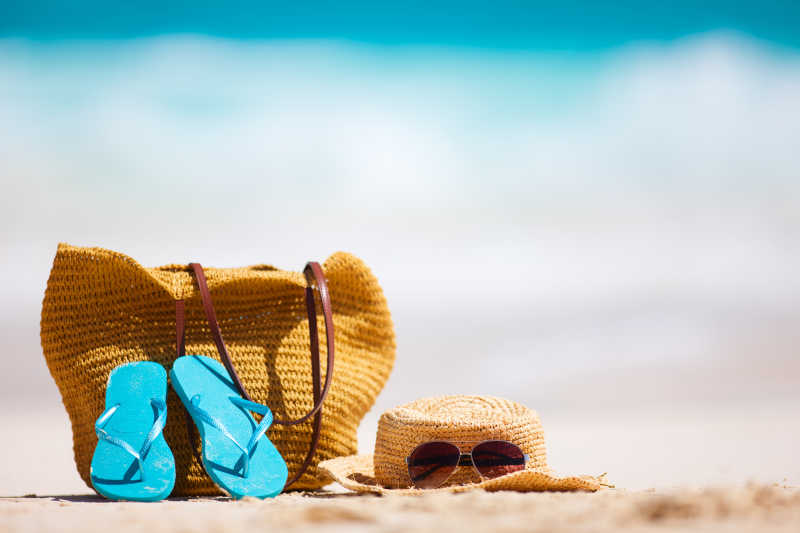 草帽包太阳镜和热带海滩上的人字拖
