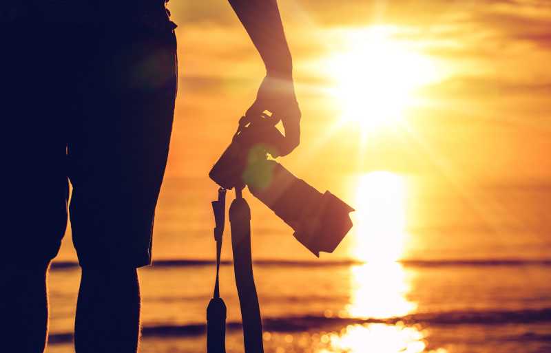 日落海滩上摄影师手里的摄影机