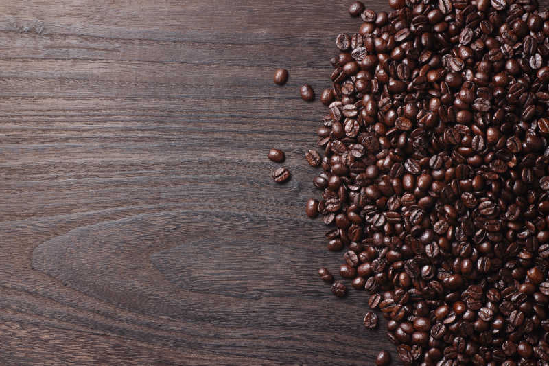 放在褐色木板上的大量咖啡豆