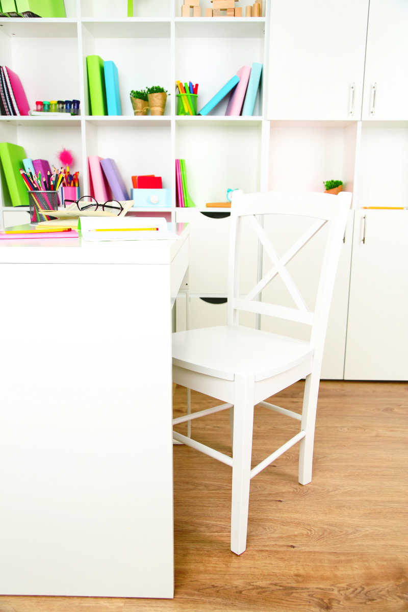 室内白色的放着书本的桌椅和放着不同文具的书架