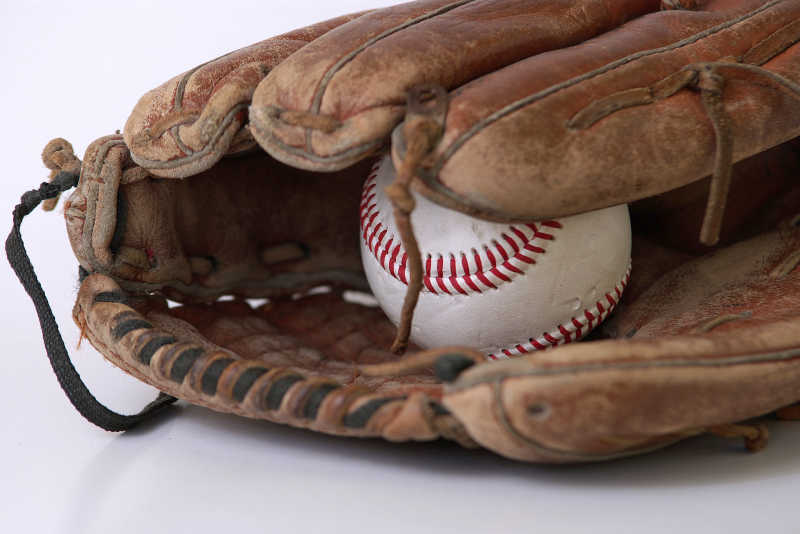 白色背景下的旧皮质棒球手套和棒球