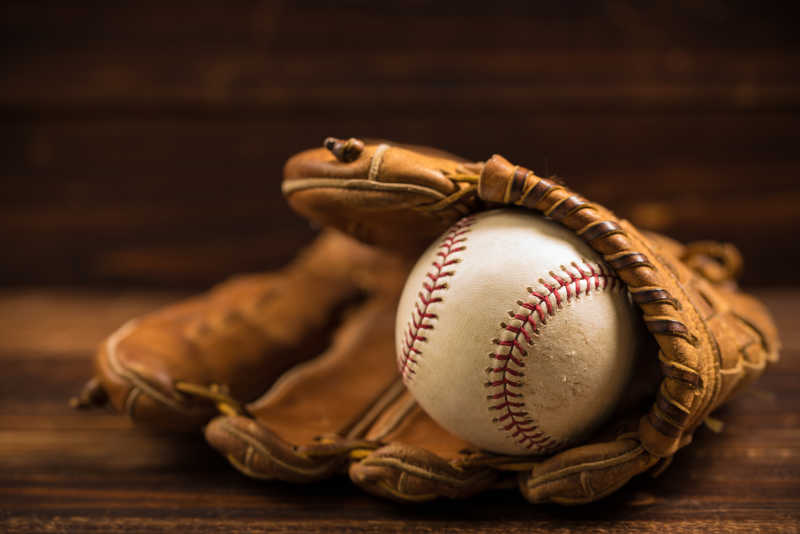 木长凳上的棕色皮质手套与棒球