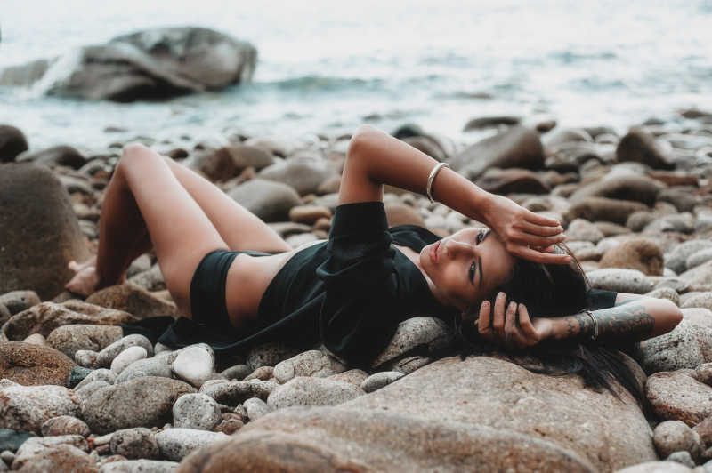 躺在海滩鹅卵石上的性感女模特