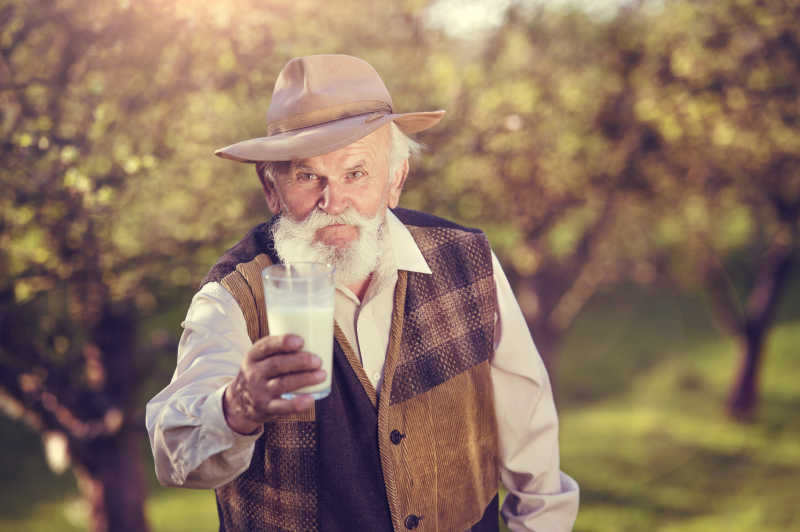 果园里的老人手里拿着一杯牛奶