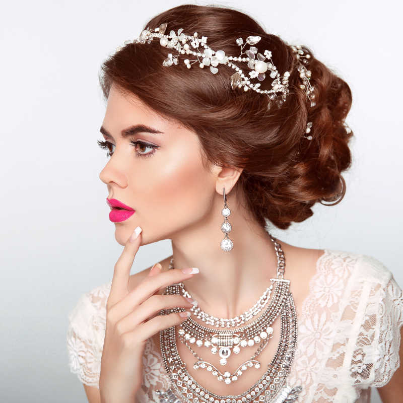 白色背景下带着珍贵珠宝的新娘模特