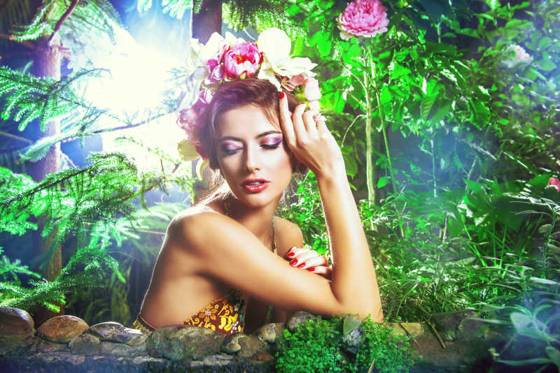 一个美丽的女孩戴着花环坐在雨林里