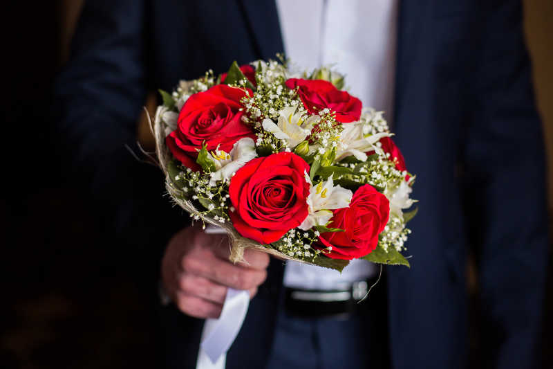 新郎手捧白色鲜花和红玫瑰花束