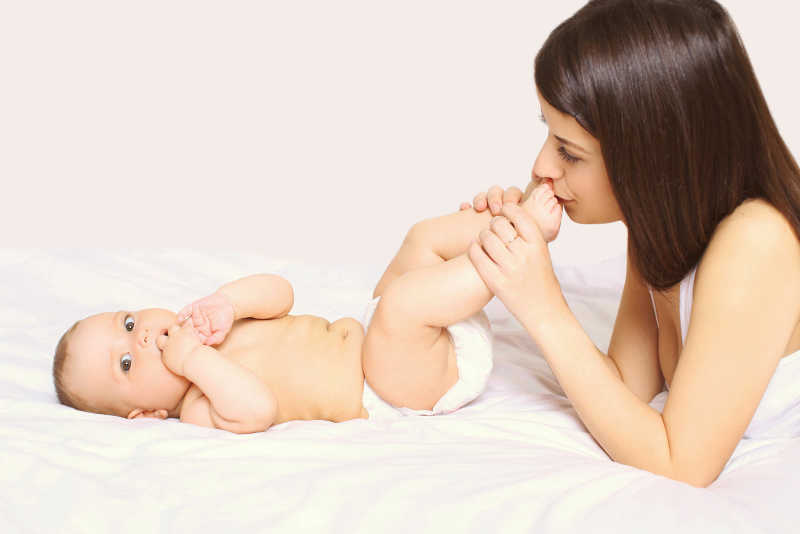 年轻母亲亲吻着婴儿的脚丫