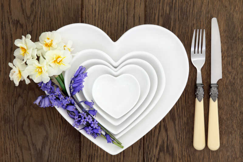 木桌上叠加的心型餐具和花朵