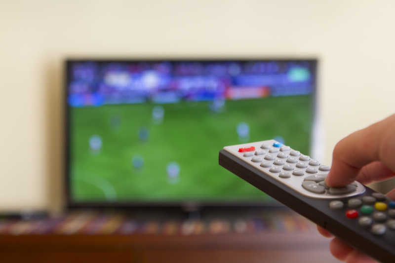 在电视上看足球比赛时使用手中的电视遥控器
