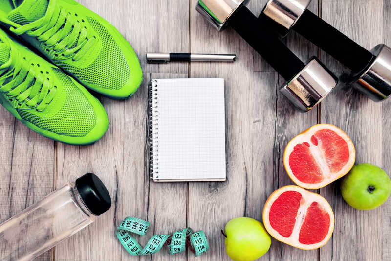 木桌上的运动健身器材水杯水果和笔记本